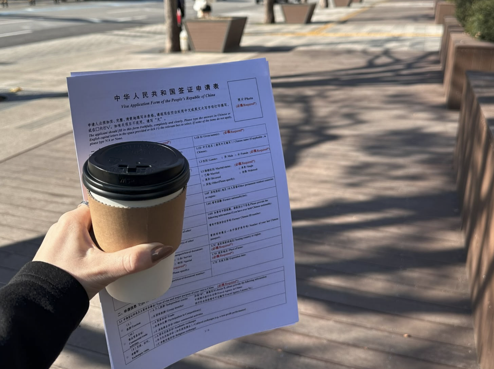 Stasia holding a China visa application and a coffee while travelling